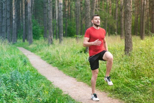 Hombre atlético joven que activa a lo largo de una pista forestal