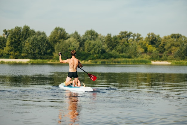 Hombre atlético monta en el río en una vista trasera de paddle board