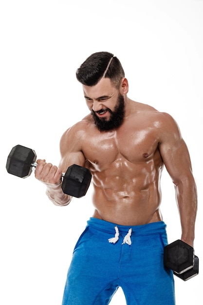 Hombre atlético musculoso haciendo ejercicios con pesas. Culturista fuerte con el torso desnudo sobre fondo blanco.