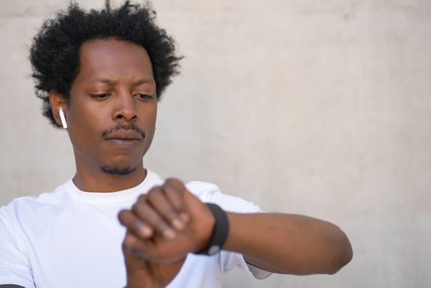 Hombre atlético que controla el tiempo en su reloj inteligente mientras hace ejercicio al aire libre. Concepto de deporte y estilo de vida saludable.