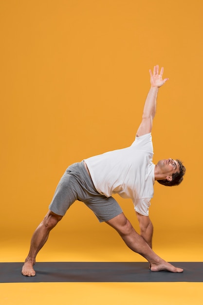 Foto hombre atlético que ejercita en la estera de yoga