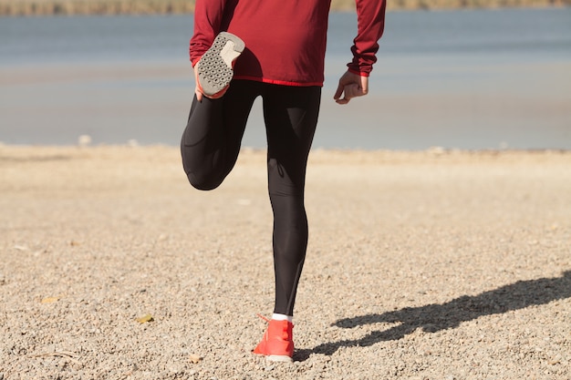 Hombre atlético en ropa deportiva que se extiende en la naturaleza