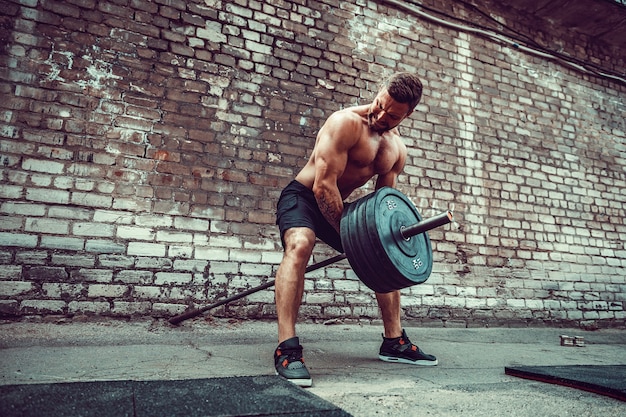 Hombre atlético trabajando con una barra. Fuerza y motivación. Ejercicio para los músculos de la espalda.