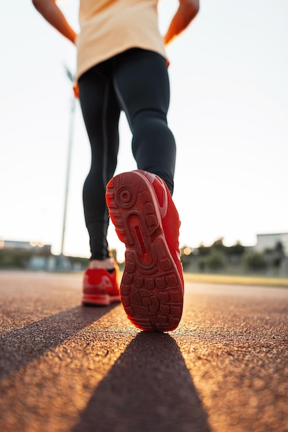 Hombre atlético en zapatillas rojas de moda corre al atardecer