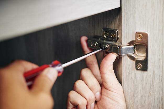 Hombre atornillando la bisagra de la puerta