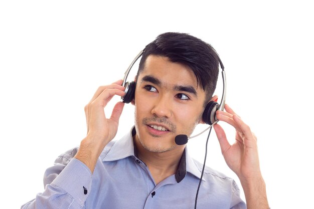 Hombre atractivo con cabello negro en camisa azul con auriculares negros sobre fondo blanco en estudio