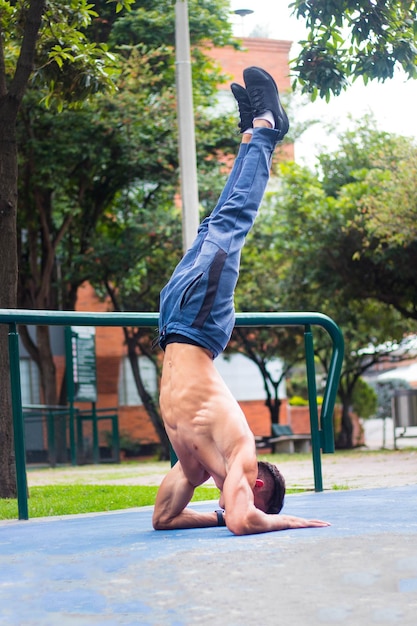 Hombre atractivo caliente haciendo una parada de manos en un parque