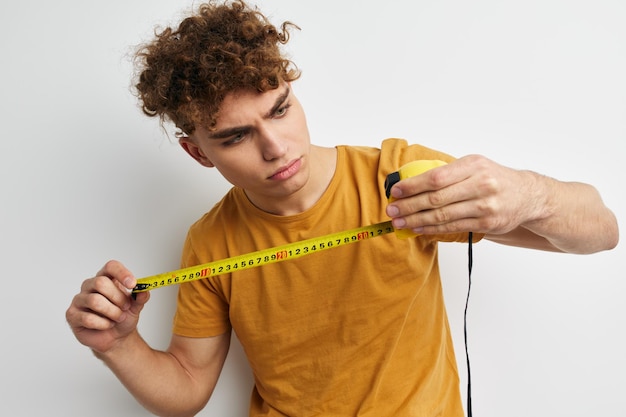 Hombre atractivo cinta métrica de medición en camiseta amarilla fondo claro