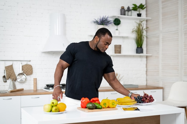 Hombre atractivo cocinando comida vegetariana de frutas. Apuesto joven eligiendo frutas saludables freah.