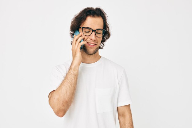 Hombre atractivo en una comunicación de camiseta blanca por teléfono de fondo aislado
