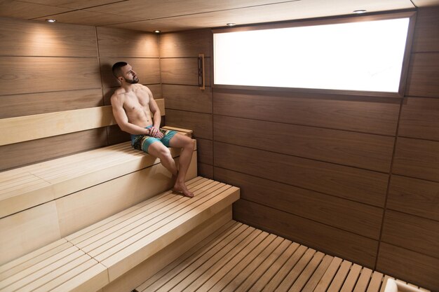 Hombre atractivo descansando relajado en la sauna