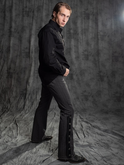 Un hombre atractivo con una elegante camisa de traje con una foto bordada en el estudio sobre un fondo gris