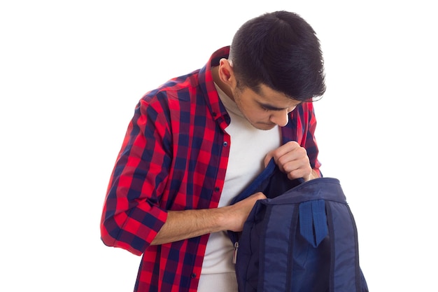 Hombre atractivo joven con cabello negro en camiseta blanca y camisa a cuadros roja con mochila azul