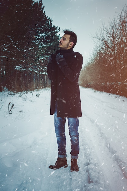 Hombre atractivo joven que abraza la nieve en invierno. Retrato de primer plano