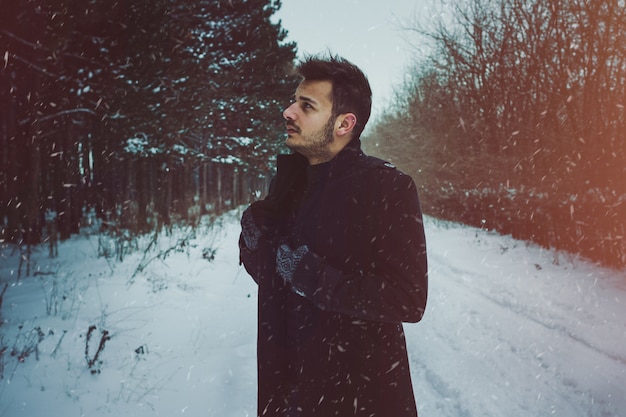 Hombre atractivo joven que abraza la nieve en invierno. Retrato de primer plano