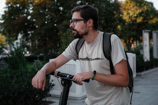 Hombre atractivo montando un patinete en el fondo del paisaje urbano