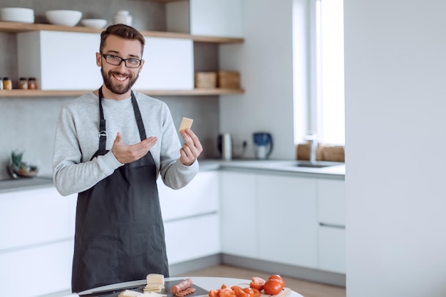 Hombre atractivo mostrando un trozo de queso delicioso