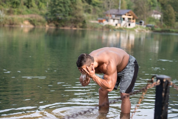 Hombre atractivo parado en el río y disfruta de la naturaleza