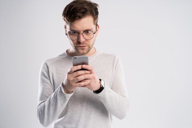 Hombre atractivo con el pelo corto charlando o escribiendo mensajes de texto con teléfono celular