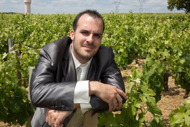 Un hombre atractivo posa para un retrato afuera en un viñedo de bodega