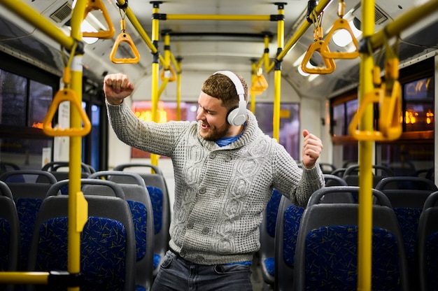 Hombre con auriculares bailando solo en el bus