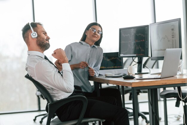 Foto el hombre está con auriculares dos empleados están trabajando en la oficina juntos