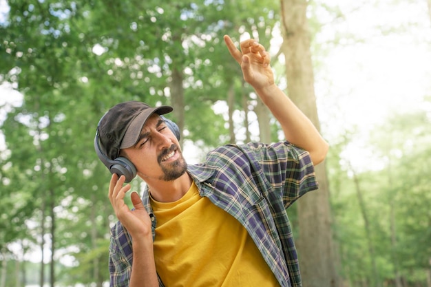 Hombre con auriculares escuchando y disfrutando de la música en el teléfono inteligente en el parque. naturaleza al aire libre.