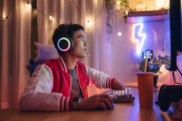 Foto un hombre con auriculares se sienta en un escritorio con una luz de neón en el fondo