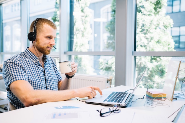 Hombre en auriculares trabajando en la computadora portátil