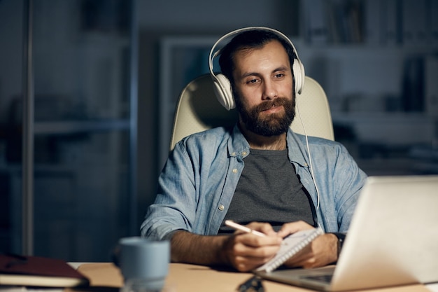 Hombre con auriculares trabajando con información en la oficina oscura