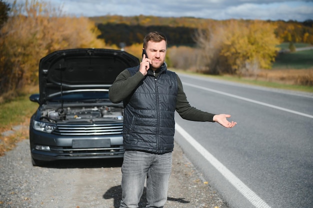 Hombre con auto roto en medio de la carretera