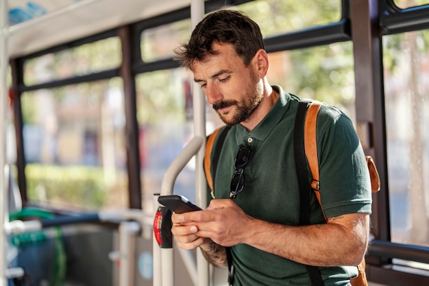 Un hombre en un autobús público está usando su teléfono