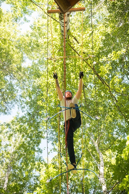 Hombre de aventura de cuerda cruzando el puente de cuerda en lo alto