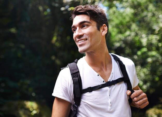 Foto hombre aventura y mochila para hacer senderismo en la selva tropical con sonrisa para pensar vacaciones y al aire libre en verano persona feliz y bolsa para hacer trekking caminar y dirección en la naturaleza para vacaciones en colombia