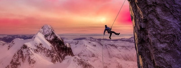 Hombre aventurero adulto descendiendo en rappel por un acantilado rocoso Compuesto de aventura extrema