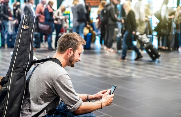 Hombre aventurero en el aeropuerto internacional mediante teléfono móvil inteligente