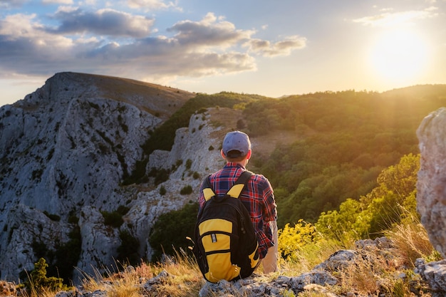 El hombre aventurero está en la cima de la montaña y disfruta de la hermosa vista durante una puesta de sol vibrante