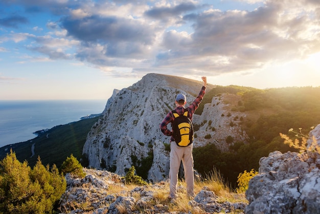 El hombre aventurero está en la cima de la montaña y disfruta de la hermosa vista durante una puesta de sol vibrante