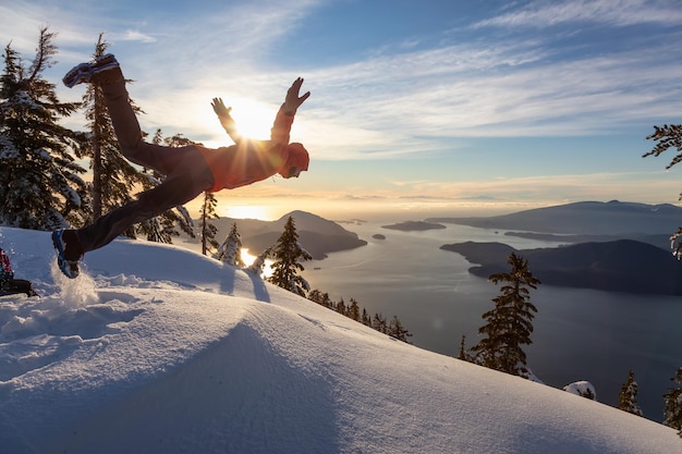 Hombre aventurero saltando en la nieve en la cima de una montaña