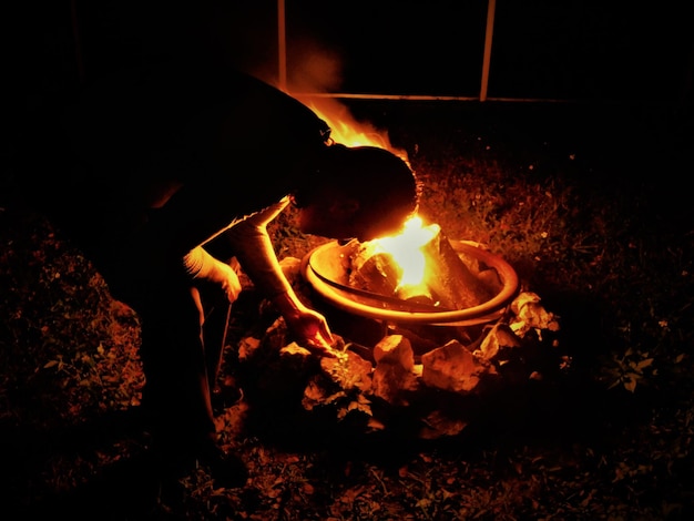 Hombre avivando una hoguera por la noche