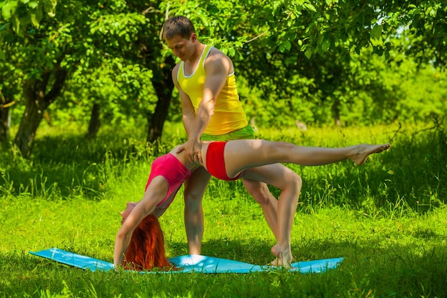 Un hombre ayudando a una mujer a hacer gimnasia.