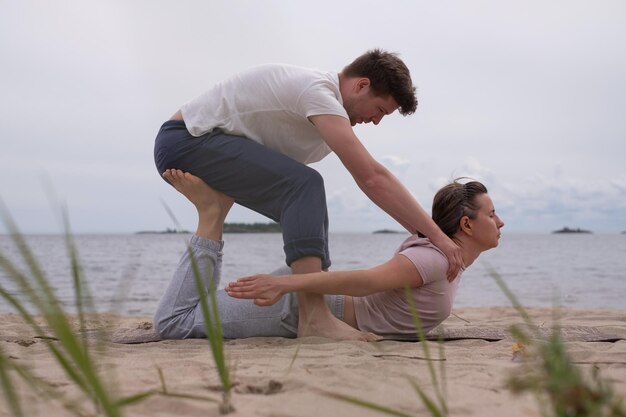 Hombre ayudando a mujer a hacer yoga bhujangasana cobra pose