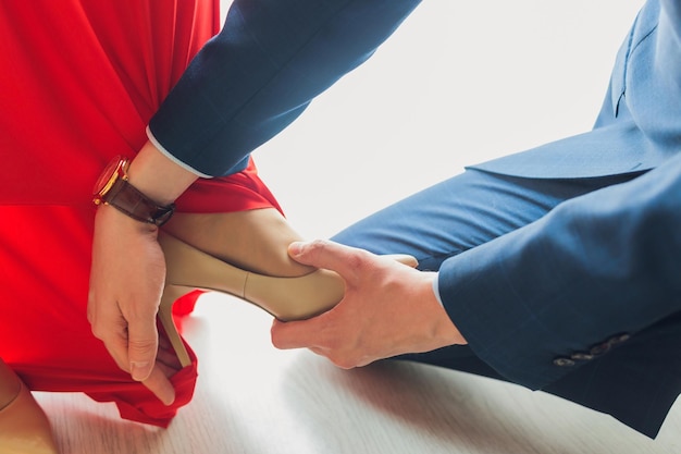 Un hombre ayudando a su esposa embarazada a ponerse los zapatos.