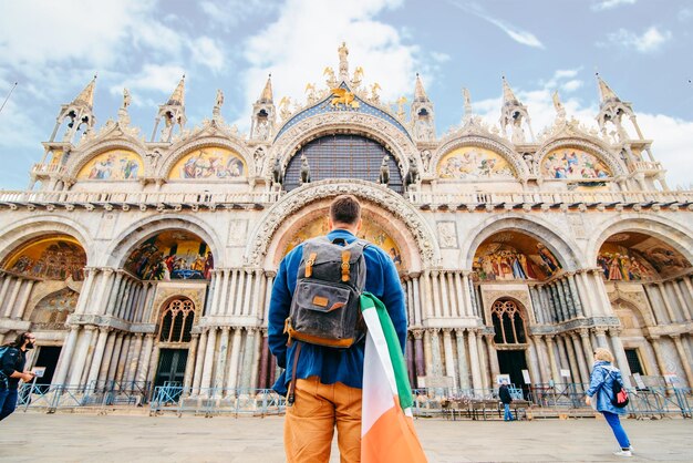 Hombre con bandera italiana mirando la basílica de san marco Venecia Italia
