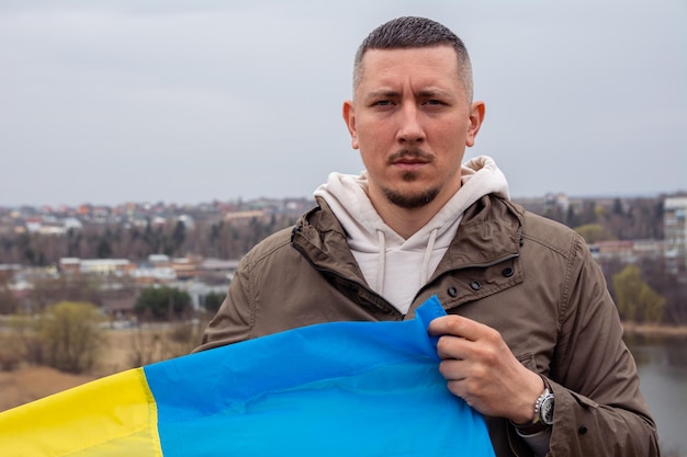 Un hombre con una bandera de Ucrania en el contexto de una ciudad y un lago en una ciudad ucraniana