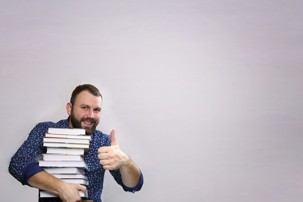 Hombre de barba adulto estudiante con pila de libro aislado sobre un fondo gris