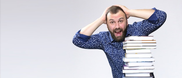 Hombre de barba adulto estudiante con pila de libro en una biblioteca