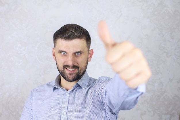 Foto un hombre con barba en una camisa hace gestos con los dedos