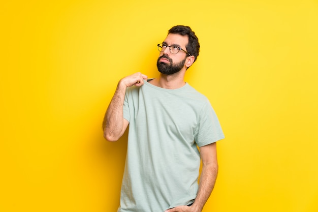 Hombre con barba y camisa verde con expresión cansada y enferma.