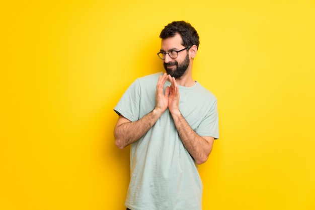 Hombre con barba y camisa verde maquinando algo.